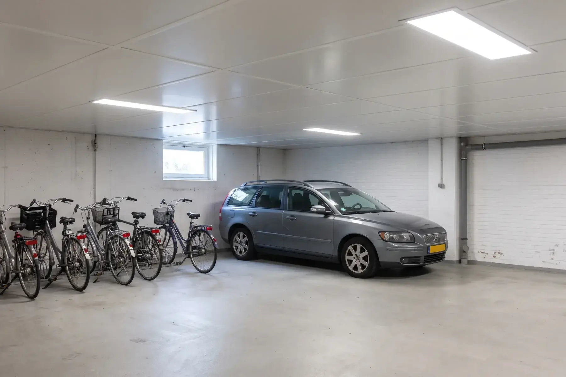 Geïsoleerd en wit afgewerkt plafond van een parkeerkelder onder appartementen