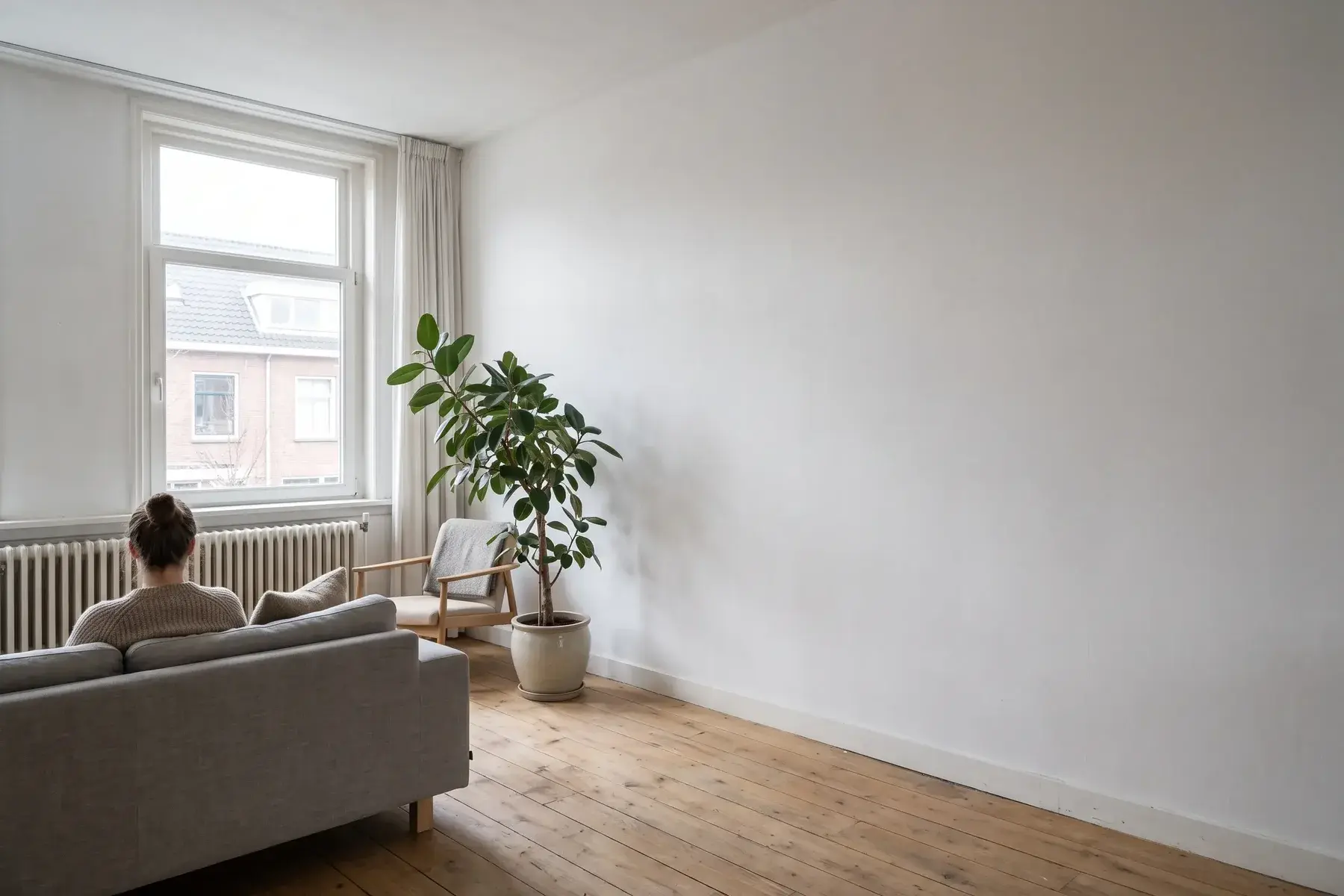 Woonkamer met een glad gestuukte, witte binnenmuur na het plaatsen van een voorzetwand